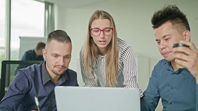 Creative business team meeting in modern start up office male team leader pointing at screen discussing diverse people group teamwork using laptop display
