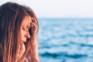 Young woman feeling sad by the sea