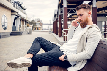 young guy with a beard and mustache posing on the street in the sunlight, fashion man, style, vintage style, retro men, handsome beard, outdoor portrait, hipster man