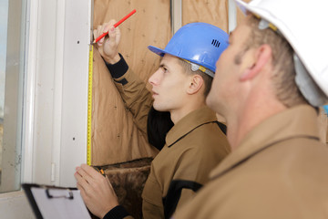 builder and architect working together measuring wall