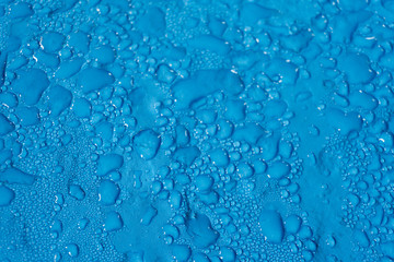 water drops of different sizes on a smooth blue surface