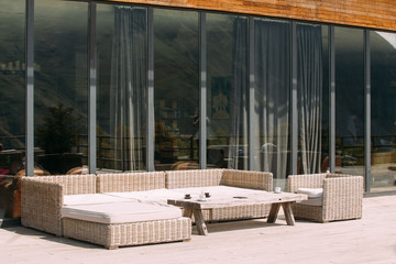 Wicker Furniture On Balcony At Sunny Summer Day. Exterior With Table