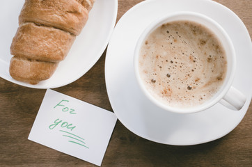 Cappuccino or coffee latte and croissant.