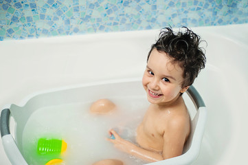 a happy child bathes in a bathroom. Little baby having soapy bath at home