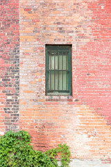 Fototapeta na wymiar barred window in brick wall with twining plants
