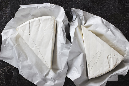 Camembert or brie cheese in white paper on black  background.