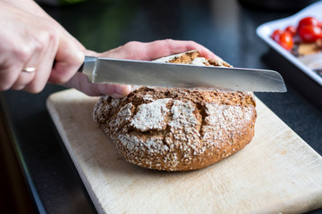 Cutting loaf of bread with knife on cutting board