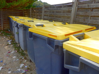 Compound of recycling bins with the ground littered in general waste.