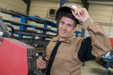 smiling welder taking off hardhat