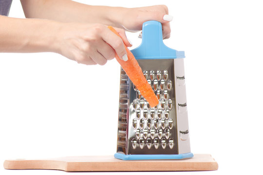 Female hand holding a kitchen grater and carrots isolated
