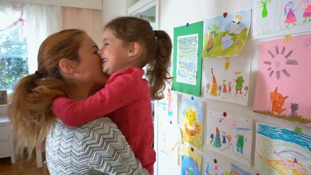 Little cute girl and her mother playing in the nursery against the wall with children's drawings. Slow motion.