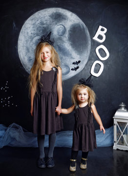 Two cute little sisters are dressed in witch costumes
