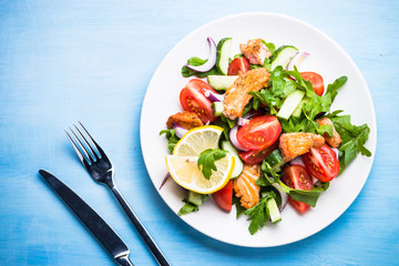Fresh salad with salmon and vegetables. Top view on blue table.