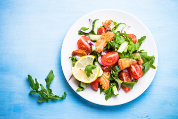 Fresh salad with salmon and vegetables on blue.
