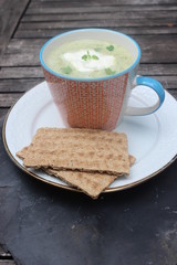 Suppe mit Schmand und Knäckebrot auf Holztisch