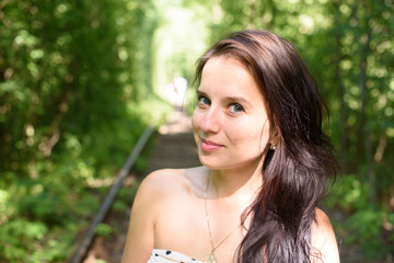 adorable beautiful young brunette woman in nice elegant dress, posing in nature on a beautiful sunny day on the railway track