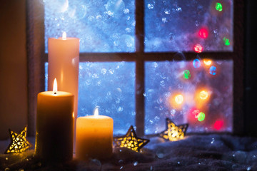 Winter decoration with candles near the snow-covered window