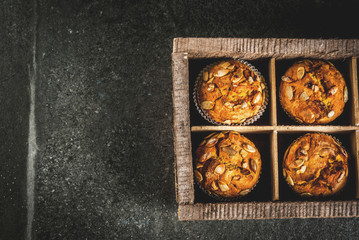 Autumn and winter baked pastries. Healthy pumpkin muffins with traditional fall spices, pumpkin seeds. In old wooden box, Black stone table, copy space top view
