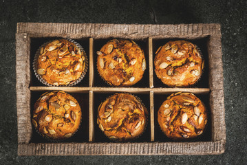 Autumn and winter baked pastries. Healthy pumpkin muffins with traditional fall spices, pumpkin seeds. In old wooden box, Black stone table, copy space top view