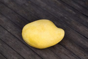 Pale yellow mango on wooden background. Tropical fruit mango on fruit market table.