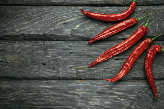 Frame of a red chili pepper of black wooden table. Rustic cuisine. Hot pepper of red color. Overhead view at red chili pepper.