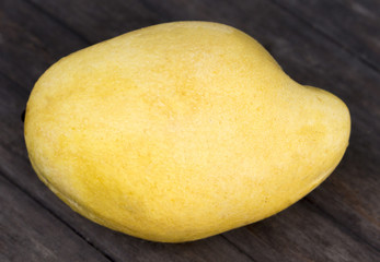 Yellow mango closeup on wooden background. Tropical fruit mango on fruit market table.