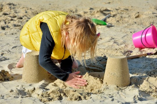 Une fillette joue au sable en bord de mer