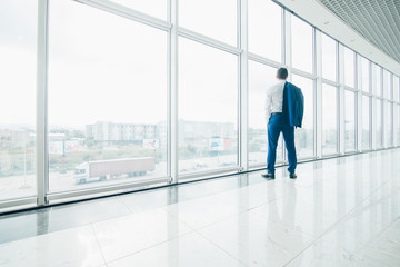 Young businessman with jacket over shoulders in modern office panoramic windows