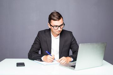 Handsome young man working with laptop in office and make notes