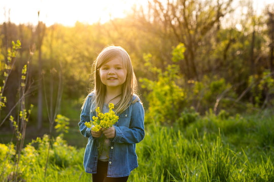 Young girl standing in field, holding flowers 