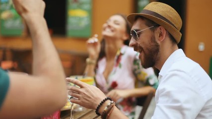 people, leisure and communication concept - happy friends meeting and drinking cocktails and eat nachos at street cafe, slow motion shot - Powered by Adobe