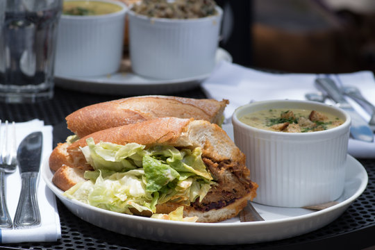 Lunch combo included crispy fresh sandwich with lettuce, sauce and meat and soup on the side served on a table outside.