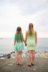 Mother and daughter are standing on the beach