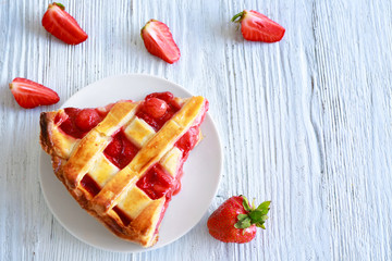 Plate with piece of delicious strawberry cake on white wooden table