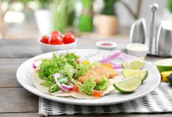 Plate with delicious fish taco on wooden table