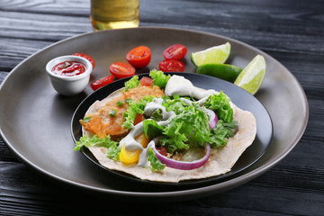 Plate with delicious fish taco on wooden table