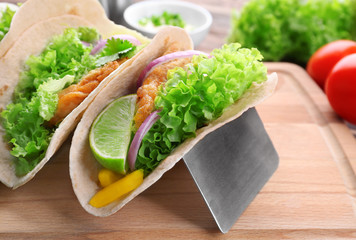 Holder with delicious fish tacos on wooden board