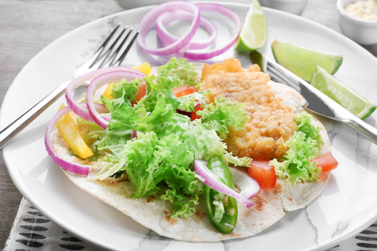 Plate with delicious fish taco on table