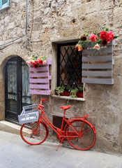 Fototapeta na wymiar Red bike in a traditional Italian medieval town, Tuscany, Italy.