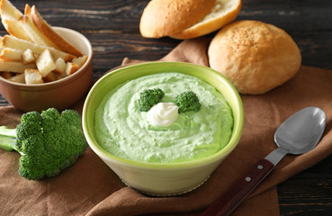 Bowl with tasty broccoli soup on table