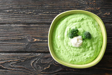 Bowl with tasty broccoli soup on wooden background