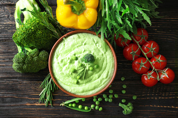 Composition with delicious broccoli soup and vegetables on wooden background