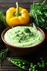 Delicious broccoli soup with pea in bowl on table