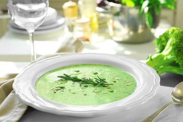 Plate with delicious creamy broccoli soup on table