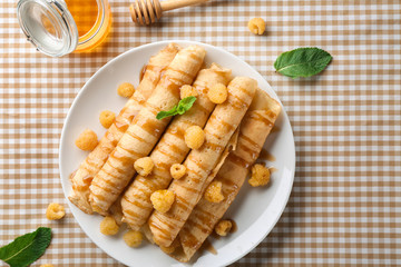Rolled thin pancakes served with yellow raspberry and honey on white plate