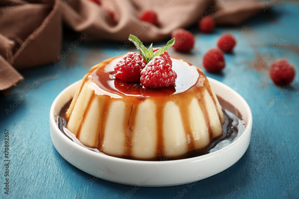 Sticker plate of delicious vanilla pudding with chocolate syrup on table