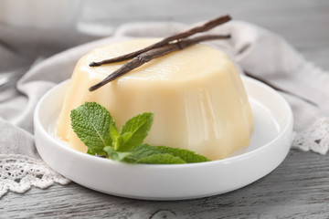 Plate with delicious vanilla pudding on table