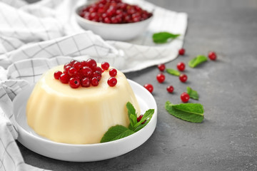 Plate with delicious vanilla pudding with red currant on table