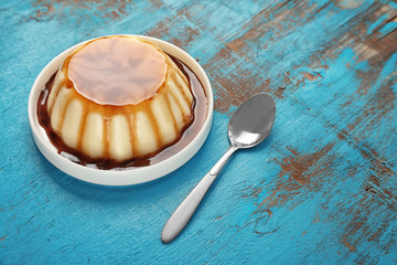 Plate of delicious vanilla pudding with chocolate syrup on table