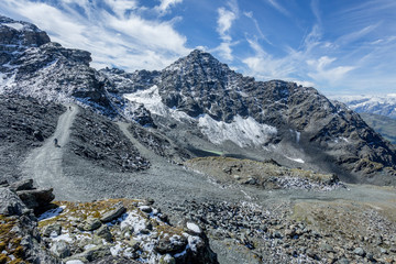 Fototapeta na wymiar une route de montagne en haute altitude, dans les Alpes avec des cyclistes qui descendent